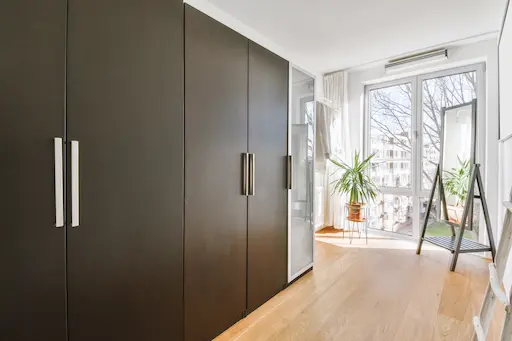 Chambre avec placards et grande fenêtre lumineuse.