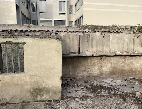 Mur délabré avec bâtiment en arrière-plan.