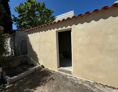 Petite construction avec porte ouverte, arbre en arrière-plan.