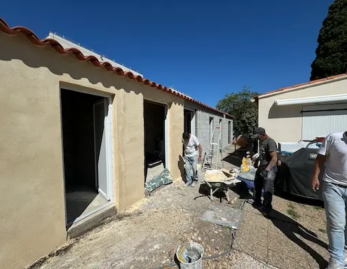 Travailleurs rénovant une maison sous le soleil.