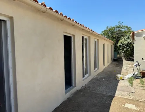 Maison avec façade beige et nouvelle toiture rouge.