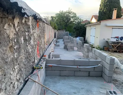 Construction de mur en parpaings dans un jardin.