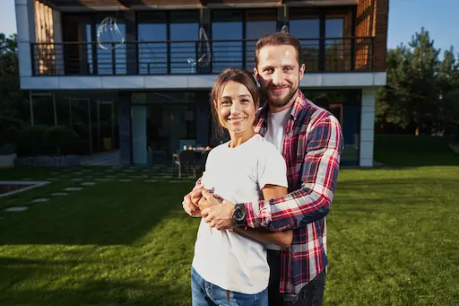 innova solution courtage pour construction neuve Couple souriant devant une maison moderne.