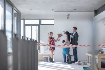 courtier travaux aménagement intérieur innova solution couple avec un enfant dans un appartement en rénovation discutant avec une dame qui a un nuancier dans la main