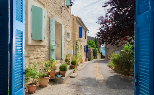 Vue de ruelle charmante entre volets bleus.