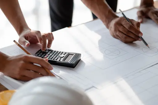 vue sur un plan d'architecte avec 2 personnes qui calculent et dessinent
