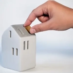 Main insère pièce dans tirelire maison.