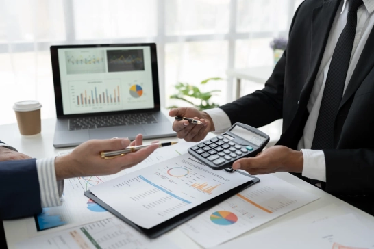 Réunion analyse financière avec ordinateur et calculatrice.