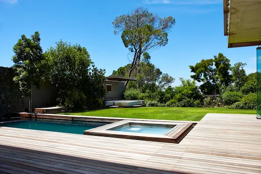 Jardin avec piscine et terrasse en bois.