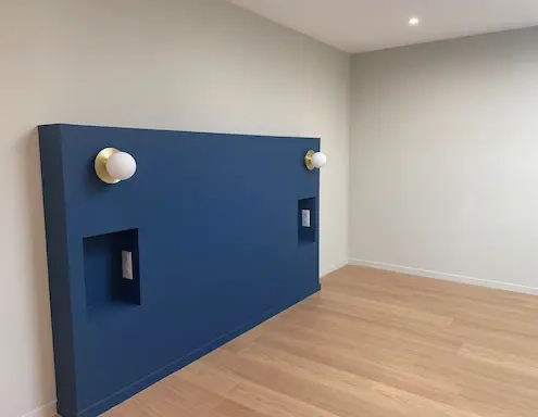 Chambre avec mur bleu et lampes murales.