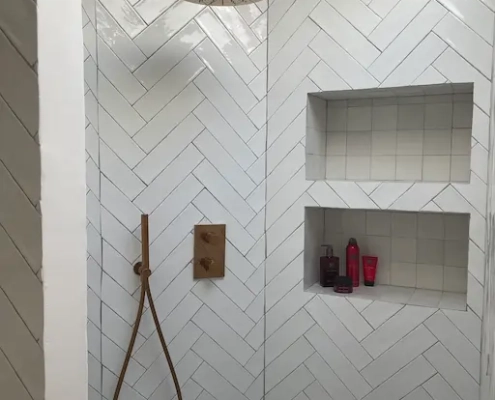 Douche moderne avec carrelage blanc et étagères encastrées.