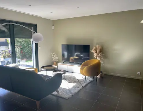 Salon moderne avec canapé, table basse et télévision.