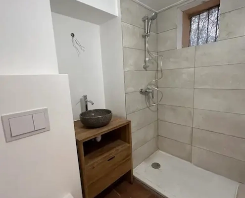 Salle de bain moderne avec douche et vasque.