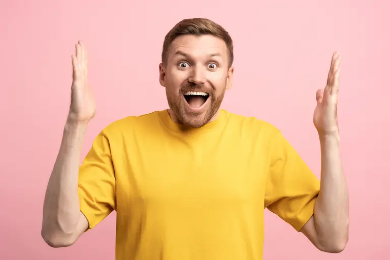Homme surpris en t-shirt jaune sur fond rose.
