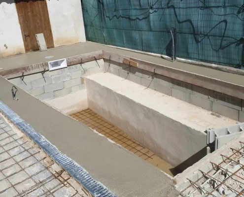 Structure maçonnée du bassin et marches visibles avant la pose des revêtements de la piscine.